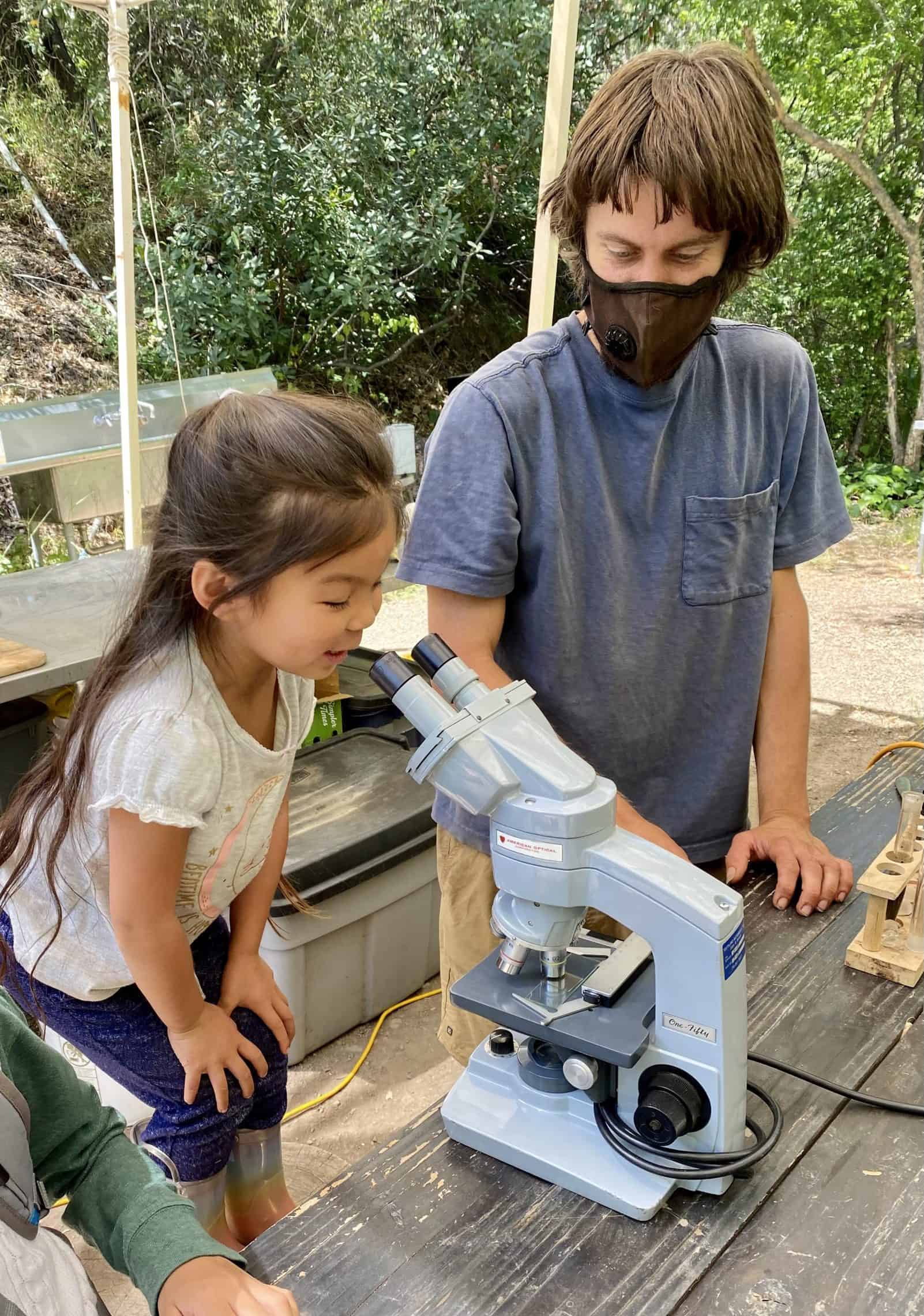 Earthroots Instructor Shane teaching a student about observing nature through a microscope